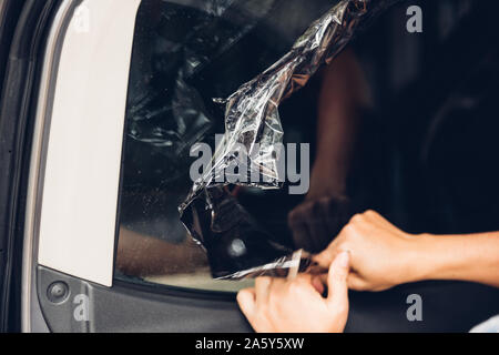 Specialist worker service peeling old film from window car Stock Photo