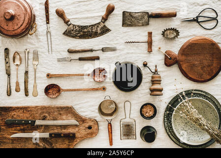 Various kitchen utensils and tablewear over rustic linen tablecloth Stock Photo
