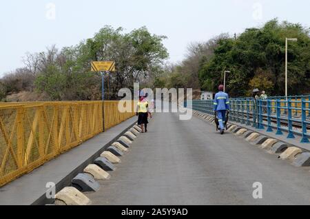 People walking over on Victoria Falls Bridge crossing the Zambezi River at the border crossing between Zambia and Zimbabwe Africa Stock Photo