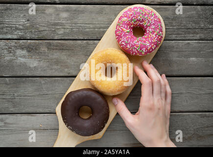 three donuts on a wooden board background with blank space Stock Photo