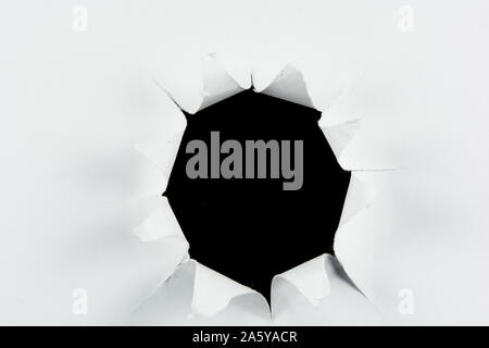 Breakthrough torn big black hole in white paper isolated background Stock Photo