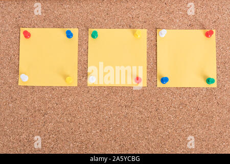 Yellow blank note papers with pin on wooden board background Stock Photo