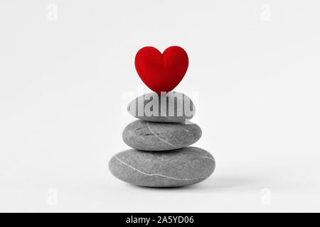 Stacked Zen stones with heart on white background - Concept of love and balance Stock Photo