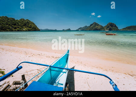 Traditional banca boat at Las cabanas beach in front of blue lagoon and exotic nature scenery in El Nido, Palawan, Philippines Stock Photo