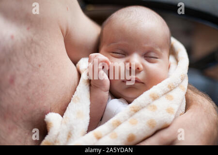 Young father holding his sweet adorable sleeping newborn child Stock Photo