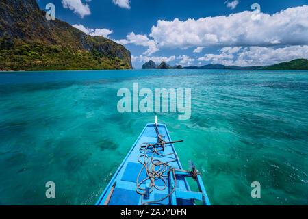 Island hopping Tour boat hover over open blue ocean water between exotic karst limestone islands on travel tour trip exploring Bacuit archipelago, El Stock Photo