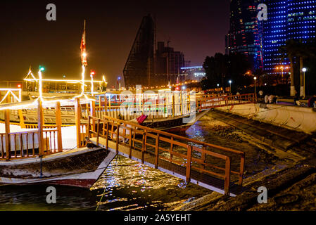 Wooden dhow boats, fitted with light strips, sit waiting for hire late in the evening on Doha's Corniche Stock Photo