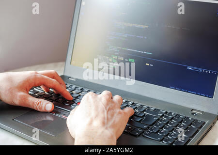 Programmer coding on laptop computer. Coder hand closeup writing program code on keyboard for project. Professional developer programming, freelance w Stock Photo