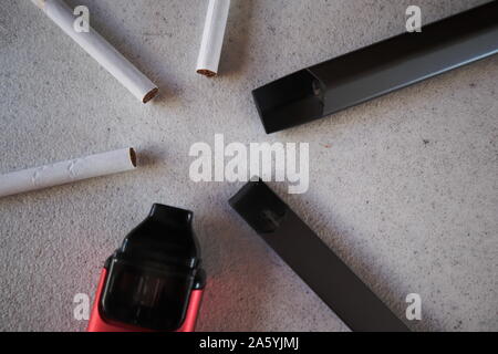 3 vape electronic cigarette devices and 3 cigarettes in a star pattern on a white textured background close up Stock Photo