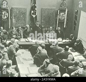 Hitler in Munich adressing a meeting of the NSDAP in 1925. Third to the left of Hitler is Alfred Rosenberg, on the right are Gregor Strasser and Heinrich Himmler. Far right by the door is Julius Streicher. Stock Photo