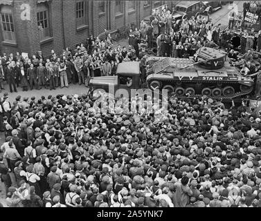 Crowds of people and a guard of honour of tanks, meeting M. Maisky, Soviet ambassador, and members of the Russian military mission when they arrived at a tank factory somewhere in Great Britain(?), where the week's tank production is for Russia, showing the 'Stalin' tank, which had just been christened by Madame Maisky 1942 or 1943. Stock Photo