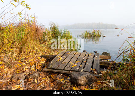 A wooden pontoon over big stones close to the blue Dnieper river is waiting for the fisherman. Stock Photo