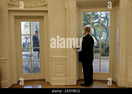 US secret service agent in the oval office, prepares to open a door as President Obama approaches Stock Photo