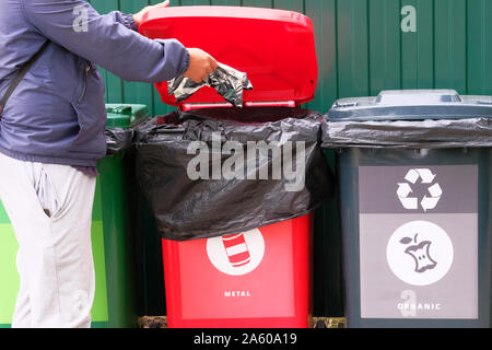 Throw metal into a container for recycling. Containers for metal, glass, paper, organics, plastic for further processing of garbage. Separate garbage Stock Photo