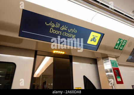 A bilingual digital sign indicating 'Doors closing' in English and Arabic on the passenger cabin on the Doha Metro, Qatar Stock Photo