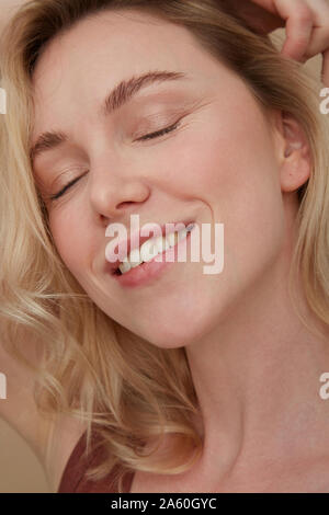 Portrait of happy blond woman wearing with eyes closed Stock Photo