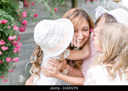 Triplet sisters hugging and kissing happy mother Stock Photo