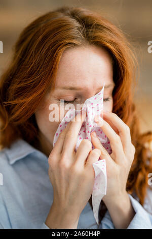 Redheaded woman blowing nose