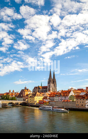 Ferry moving on Danube River by St. Peter's Church in Regensburg, Germany Stock Photo