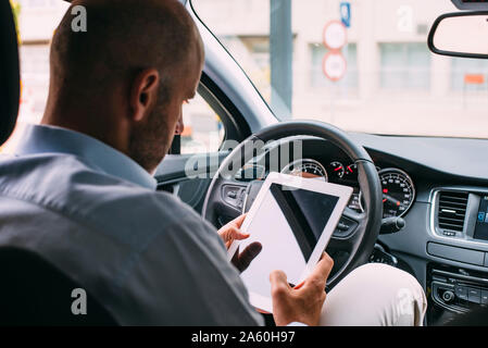 Businessman driving vehicle and using tablet Stock Photo