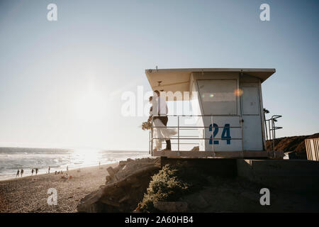 Bride and groom at lifeguard hut on the beach at sunset Stock Photo