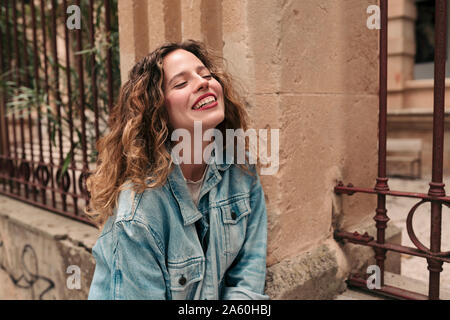 Happy young woman with curly hair and glasses in the city