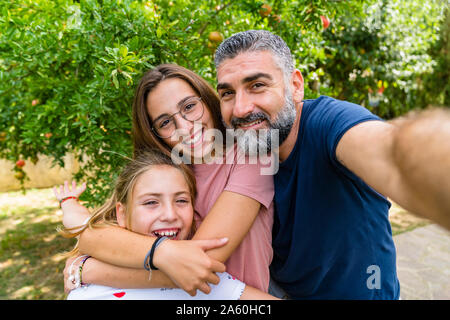 Happy father with two daughters taking selfie in garden Stock Photo