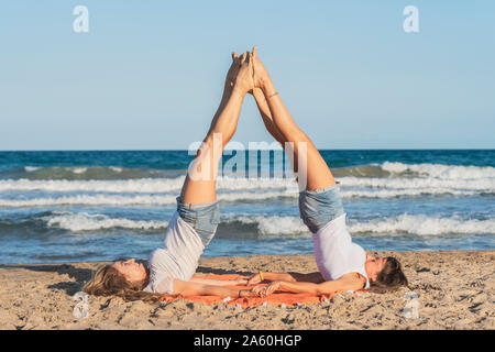 Two women praticing Acro Yoga on the beach Stock Photo