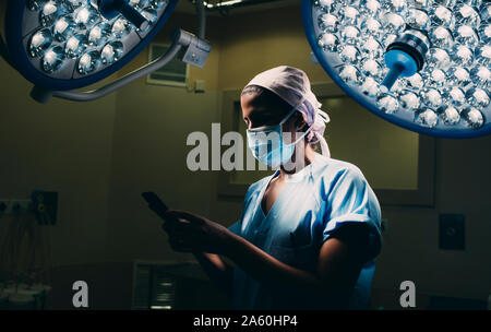 Nurse using a mobile phone in operating room Stock Photo