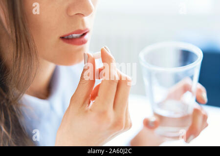 Close up of woman taking pill Stock Photo