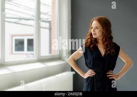Portrait of redheaded businesswoman  in a loft looking out of window Stock Photo