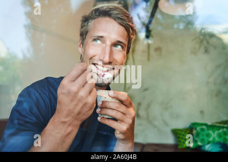 Portrait of smiling young man eating muesli Stock Photo