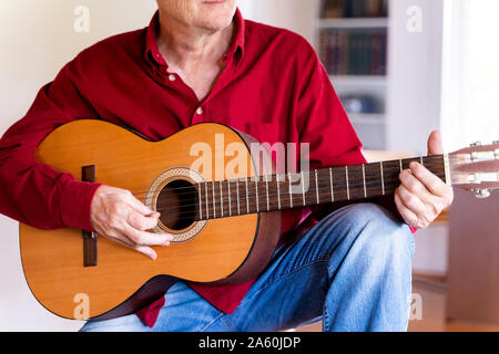 Senior man playing guitar at home Stock Photo