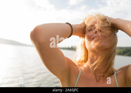 Young woman with windswept hair at a lake