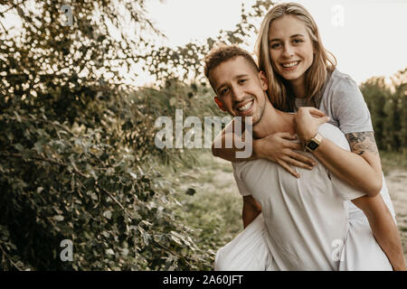 Portrait of young smiling couple, man carrying woman on back Stock Photo