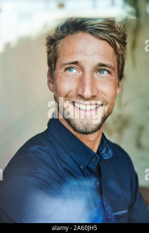 Portrait of smiling young man behind windowpane Stock Photo