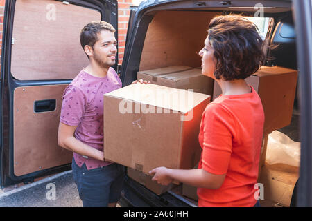 Couple unloading cardboard boxes from van Stock Photo