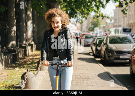 Portrait of happy teenage girl riding scooter in the city Stock Photo