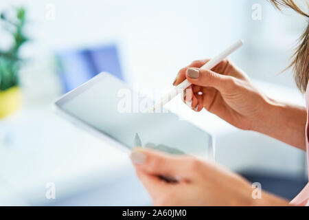 Close up of woman using pen and tablet in office Stock Photo