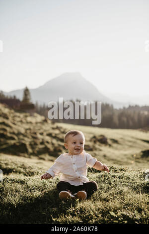 Happy little boy sitting on an alpine meadow, Schwaegalp, Nesslau, Switzerland Stock Photo