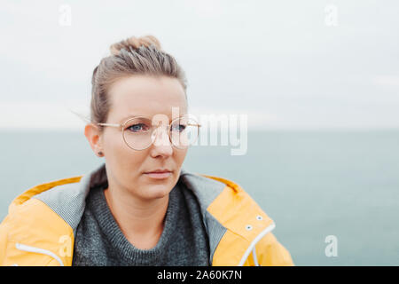 Portrait of blond woman wearing yellow rain jacket Stock Photo