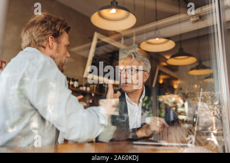 Two businessmen with laptop meeting in a cafe Stock Photo