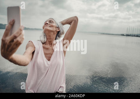 Senior woman taking smartphone selfies at the sea Stock Photo
