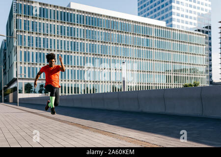 Young man jumping in the city, listening to music Stock Photo