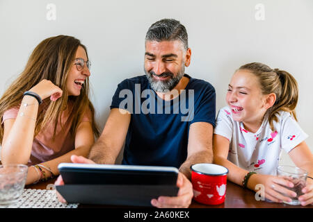 Happy father with two daughters using tablet at home Stock Photo