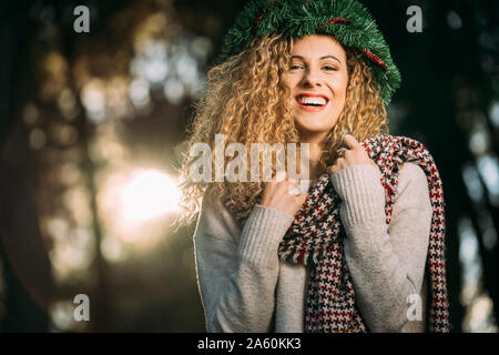 Portrait of laughing young woman wearing Christmas wreath on her head Stock Photo