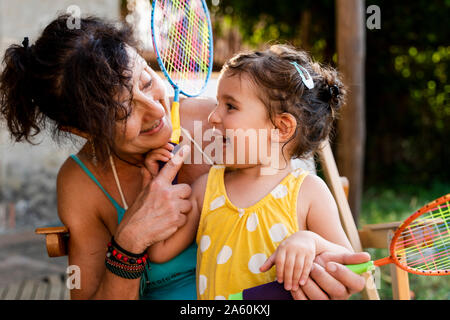 Grandmother playing with little girl and badminton rackets outdoors Stock Photo