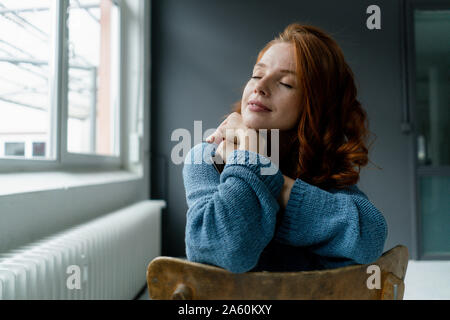 Portrait of redheaded woman with digital tablet relaxing in a loft