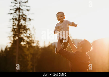 Happy father lifting up little son outdoors at sunset, Schwaegalp, Nesslau, Switzerland Stock Photo