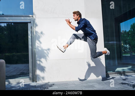 Young businessman jumping mid-air in the city Stock Photo